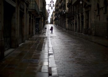 Un hombre camina por una calle vacía en el centro de Barcelona, España, el lunes 20 de abril de 2020, durante la cuarentena para combatir el coronavirus. (AP Foto/Emilio Morenatti)