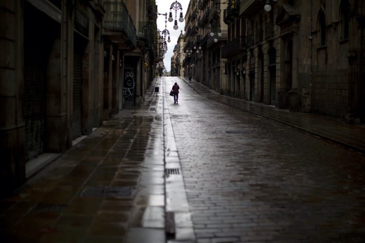 Un hombre camina por una calle vacía en el centro de Barcelona, España, el lunes 20 de abril de 2020, durante la cuarentena para combatir el coronavirus. (AP Foto/Emilio Morenatti)