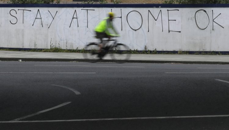 Un ciclista pasa junto a una pintada en Londres en la que se lee: "Quédate en casa, de acuerdo". También el país vive la cuarentena para combatir la expansión del coronavirus. Foto: AP Foto/Kirsty Wigglesworth.