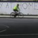 Un ciclista pasa junto a una pintada en Londres en la que se lee: "Quédate en casa, de acuerdo". También el país vive la cuarentena para combatir la expansión del coronavirus. Foto: AP Foto/Kirsty Wigglesworth.