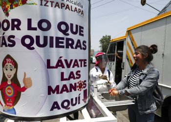 Una trabajadora municipal con equipo protector invita a una ciudadana a lavarse las manos en un lavabo portátil en la Ciudad de México el miércoles 22 de abril de 2020.  Foto: Eduardo Verdugo/AP.