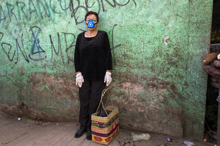 Carmen Villanueva, con una máscara de respirador y guantes desechables, espera a su hija durante un viaje de compras a un mercado popular en Lima, Perú, el sábado 4 de abril de 2020. Debido a la emergencia de salud por la propagación del nuevo coronavirus, el gobierno está restringiendo el movimiento de las personas por género. Foto AP/Rodrigo Abd.
