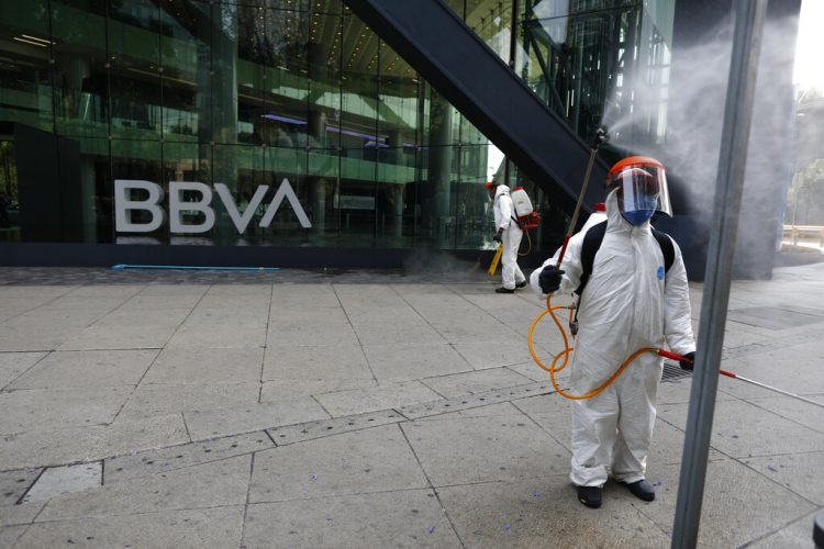 Trabajadores municipales rocían desinfectante frente al edificio del banco BBVA sobre la avenida Paseo de la Reforma en la Ciudad de México. Foto: Rebecca Blackwell/AP.