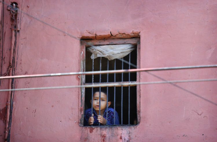 Un niño mira por la ventana de su casa en el barrio viejo de Nueva Delhi, India. Foto: Manish Swarup/Ap.