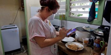 Una mujer revisa su teléfono en la cocina de su casa el 6 de abril de 2020 en La Habana. Foto: EFE/Ernesto Mastrascusa