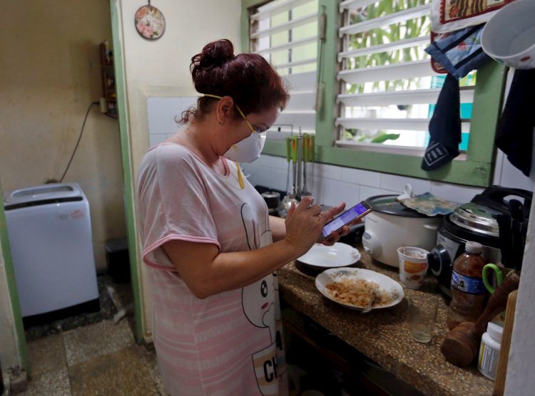 Una mujer revisa su teléfono en la cocina de su casa el 6 de abril de 2020 en La Habana. Foto: EFE/Ernesto Mastrascusa