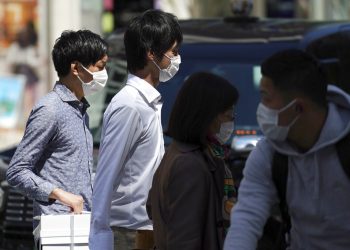Varias personas, con mascarilla para ayudar a frenar la propagación del coronavirus, cruzan un paso de peatones, en Tokio, Japón, el 10 de abril de 2020. (AP Foto/Eugene Hoshiko)