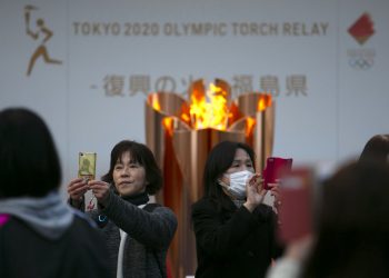 Dos mujeres se toman fotografías delante de la llama olímpica durante una ceremonia en Fukushima, Japón, en marzo de 2020. Foto/Jae C. Hong / AP / Archivo.