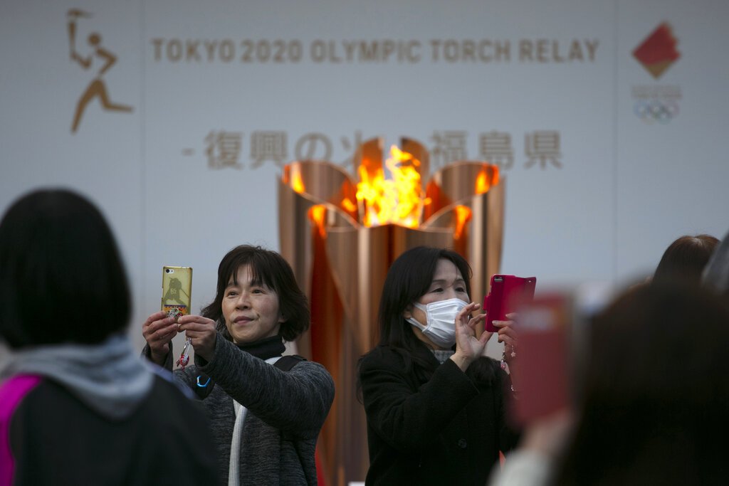 Dos mujeres se toman fotografías delante de la llama olímpica durante una ceremonia en Fukushima, Japón, en marzo de 2020. Foto/Jae C. Hong / AP / Archivo.