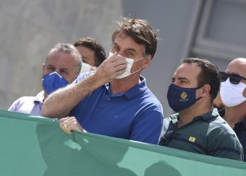 El presidente Jair Bolsonaro tocándose su nasobuco durante una protesta contra el Supremo Tribunal Federal y el Congreso Nacional en Brasilia. Foto: André Borges/AP.
