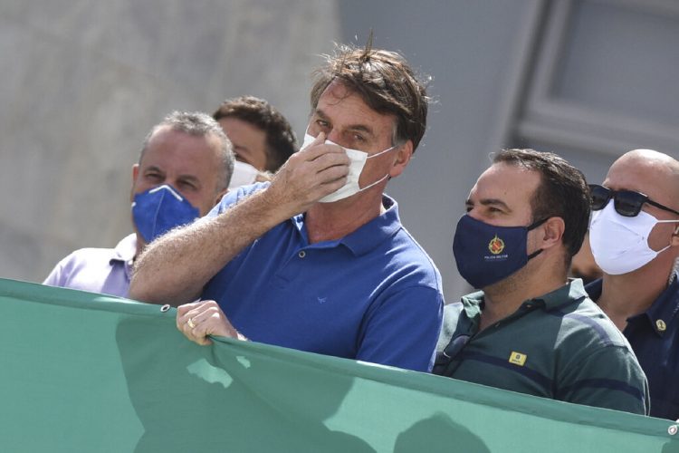 El presidente Jair Bolsonaro tocándose su nasobuco durante una protesta contra el Supremo Tribunal Federal y el Congreso Nacional en Brasilia. Foto: André Borges/AP.