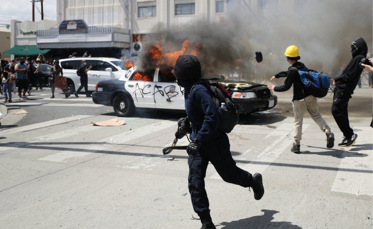 Agentes antidisturbios en Los Ángeles, California, se enfrentaron con manifestantes que incendiaron al menos dos patrullas y dañaron a otros. Foto: AP.