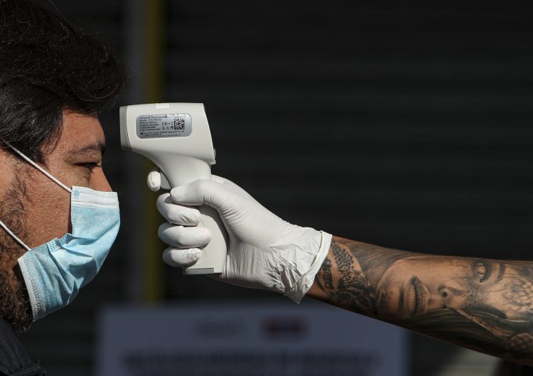 Un trabajador de la ciudad mide la temperatura de un hombre antes de ingresar al centro comercial Apumanque, en el barrio de Las Condes, en Santiago de Chile. Foto: Esteban Félix/AP