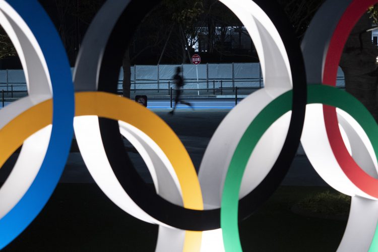 Un hombre corre por detrás de los anillos olímpicos, en Tokio. Foto: Ap/Jae C. Hong, archivo.