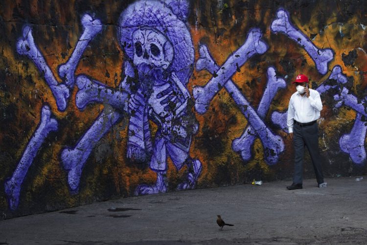 El responsable de varios cementerios públicos camina ante un mural de un esqueleto y huesos en el exterior del Panteón San Nicolás Tolentino, Iztapalapa, Ciudad de México. Foto: Marco Ugarte/AP.