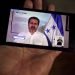 Un hombre mira a través de su móvil la transmisión de la comparecencia del presidente de Honduras, Juan Orlando Hernández, mientras anuncia que ha contraído la COVID-19, al igual que su esposa, Ana García en Tegucigalpa. Foto: Gustavo Amador/EFE