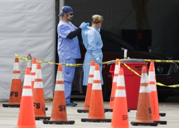 Trabajadores de la salud se ayudan mutuamente a colocarse equipo protector en un sitio de testeo del coronavirus en Miami Gardens, Florida, 5 de julio de 2020. 
Foto: Wilfredo Lee/Ap.