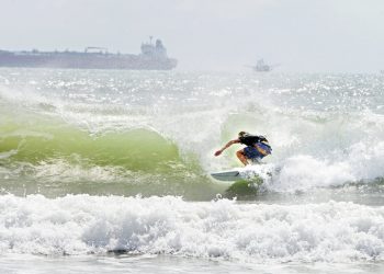 Un surfista se desplaza a orillas de la isla del Padre Sur el viernes 24 de julio de 2020 en medio de un mar picado debido a la tormenta tropical Hanna. (Miguel Roberts/The Brownsville Herald vía AP)