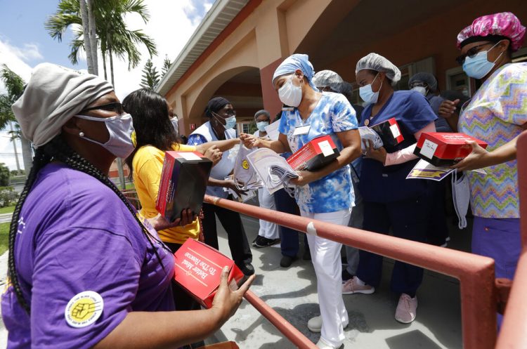 Trabajadores entregan cubrebocas para prevenir el contagio del coronavirus en una residencia y centro de rehabilitación de ancianos en Miami, 20 de julio de 2020. Foto: Wilfredo Lee/AP.