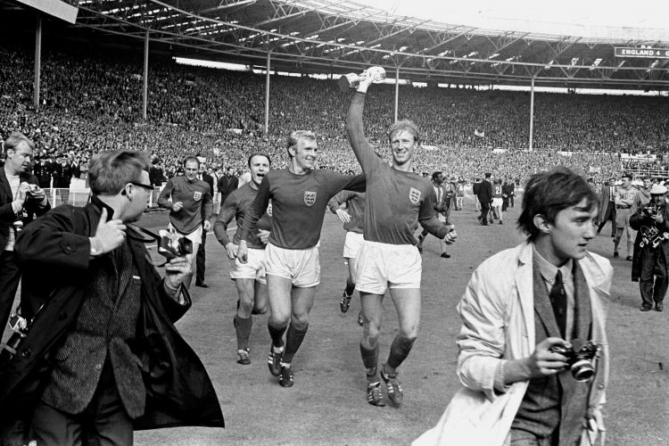 El 30 de julio de 1966 el inglés Jack Charlton sostiene la copa Jules Rimet mientras saluda al público en Wembley acompañado de su compañero Bobby Moore luego de derrotar 4-2 a Alemania Occidental. Foto: PA via AP.