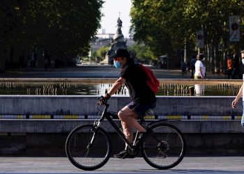 Un hombre circula en bicicleta y con mascarilla por el centro de la ciudad de Valladolid (España) donde este viernes las temperaturas superarán los 35 grados centígrados. Foto: EFE/Nacho Gallego.