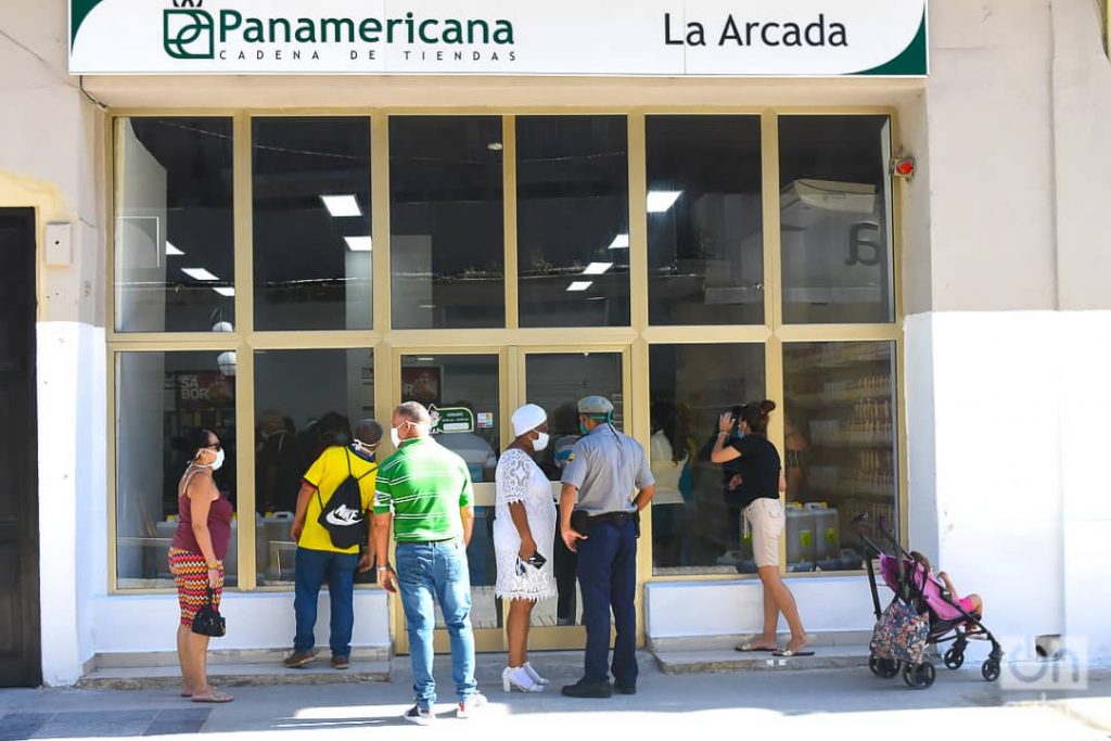 Personas conversan con autoridades y observan a través de las vidrieras de la tienda La Arcada, en la calle San Rafael de La Habana, una de las nuevas tiendas que iniciaron la venta de artículos en Moneda Libremente (MLC) este lunes 20 de julio de 2020. Foto: Otmaro Rodríguez.