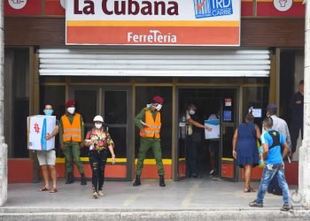 Compradores y policías en las afueras de la tienda La Cubana, de la calle Reina en La Habana, una de las nuevas tiendas que iniciaron la venta de artículos en Moneda Libremente (MLC) este lunes 20 de julio de 2020, como parte de las nuevas medidas económicas del gobierno cubano. Foto: Otmaro Rodríguez.