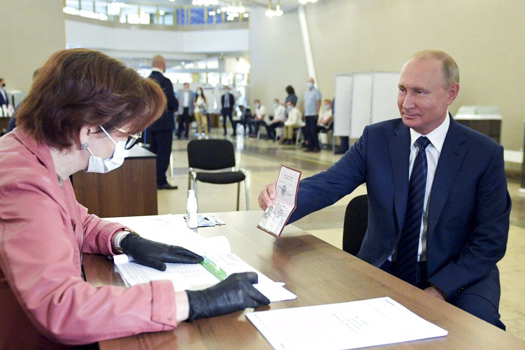 El presidente ruso Vladimir Putin muestra su pasaporte a una trabajadora electoral poco antes de votar el miércoles 1 de julio de 2020, en Moscú. Foto: Alexei Druzhinin/Sputnik vía AP.