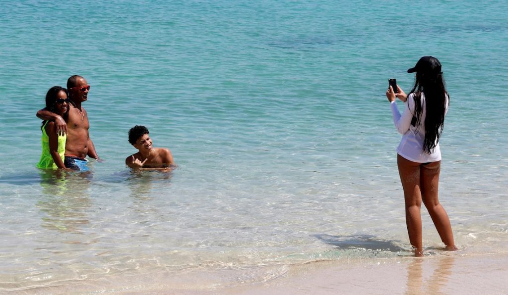 Varias personas se toman fotos mientras disfrutan de un baño en la playa durante el primer día de reapertura en La Habana durante la pandemia de coronavirus, en julio de 2020. Foto: Ernesto Mastrascusa / EFE / Archivo.