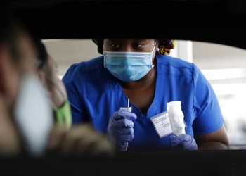 Fotografía de archivo del 24 de julio de 2020 de la trabajadora de salud Rahaana Smith explicando a personas cómo usar un hisopo nasal en un sitio de aplicación de pruebas de COVID-19, sin necesidad de bajar del auto, en el Miami-Dade County Auditorium, en Miami. (AP Foto/Wilfredo Lee, Archivo)