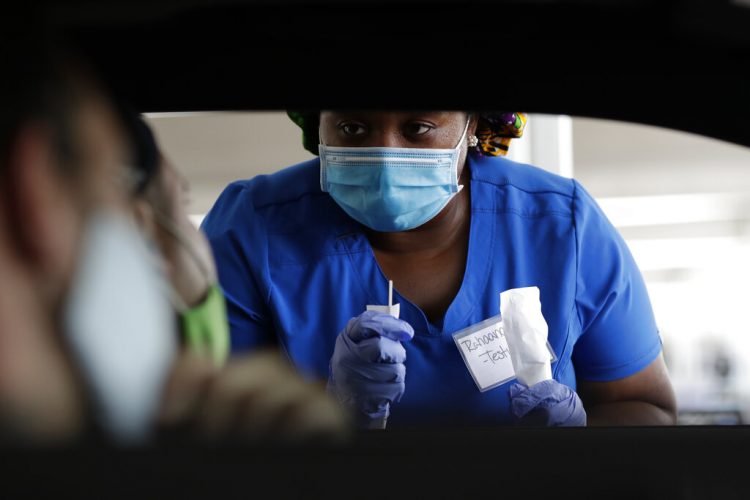 Fotografía de archivo del 24 de julio de 2020 de la trabajadora de salud Rahaana Smith explicando a personas cómo usar un hisopo nasal en un sitio de aplicación de pruebas de COVID-19, sin necesidad de bajar del auto, en el Miami-Dade County Auditorium, en Miami. (AP Foto/Wilfredo Lee, Archivo)