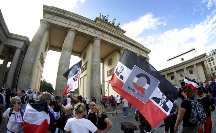 Personas con banderas con la cara del presidente estadounidense Donald Trump asisten a una manifestación contra las restricciones por la pandemia frente a la Puerta de Brandenburgo en Berlín, Alemania, el sábado 29 de agosto de 2020. (AP Foto/Michael Sohn)
