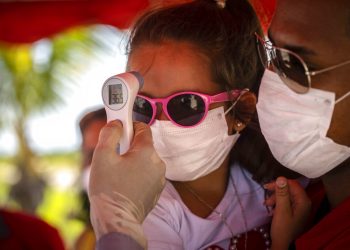 A una niña con mascarilla para protegerse del nuevo coronavirus le toman la temperatura en un puesto de control policial en la entrada de la provincia de La Habana, Cuba, el lunes 10 de agosto de 2020. Foto: AP/Ramón Espinosa.