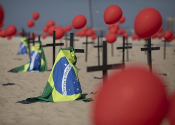 Cruces, globos rojos y la bandera de Brasil son colocados en la playa de Copacabana por el organismo no gubernamental Río de Paz en honor a las víctimas de COVID-19, en Río de Janeiro, Brasil, el sábado 8 de agosto de 2020.  Foto:Mario Lobao/AP.