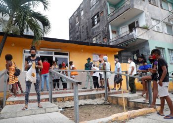 Varias personas con nasobuco hacen cola para comprar pan ante la proximidad de la tormenta Laura, en La Habana, provincia que reportó la mayor cantidad de nuevos casos hoy. Foto: Yander Zamora/EFE.