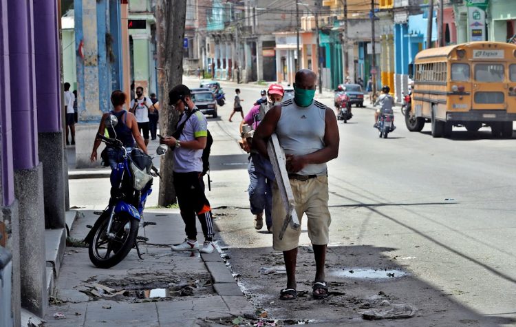 Varias personas caminan por una calle de La Habana tras el paso de la tormenta tropical Laura. Foto: Ernesto Mastrascusa/EFE.