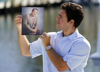 Freddy Vallejo Jr. muestra una foto de su abuelo Jorge Vallejo, el patriarca de la familia, un médico cubano que emigró e hizo su vida en la Florida. El abuelo y uno de sus hijos, Carlos, ambos médicos, fallecieron por el coronavirus. Foto: Lynne Sladky / AP.