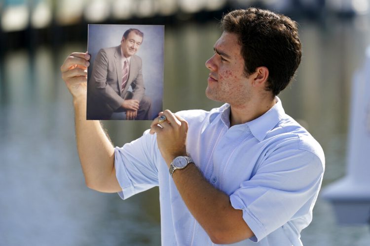 Freddy Vallejo Jr. muestra una foto de su abuelo Jorge Vallejo, el patriarca de la familia, un médico cubano que emigró e hizo su vida en la Florida. El abuelo y uno de sus hijos, Carlos, ambos médicos, fallecieron por el coronavirus. Foto: Lynne Sladky / AP.