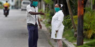 Un hombre y una trabajadora de la salud, cubiertos con tapabocas, fueron registrados este jueves al conversar en una calle de La Habana. Foto: EFE/Yander Zamora.