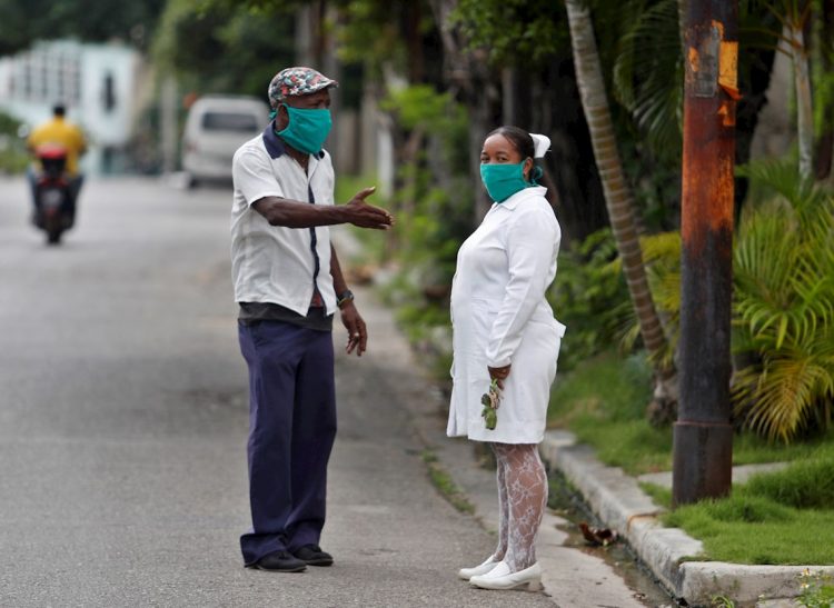 Un hombre y una trabajadora de la salud, cubiertos con tapabocas, fueron registrados este jueves al conversar en una calle de La Habana. Foto: EFE/Yander Zamora.