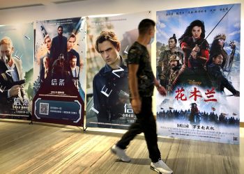 Un hombre con mascarilla pasa junto a un afiche de la película de Disney "Mulan" en un cine en Beijing, el 11 de septiembre del 2020.  Foto: Mark Schiefelbein/AP.