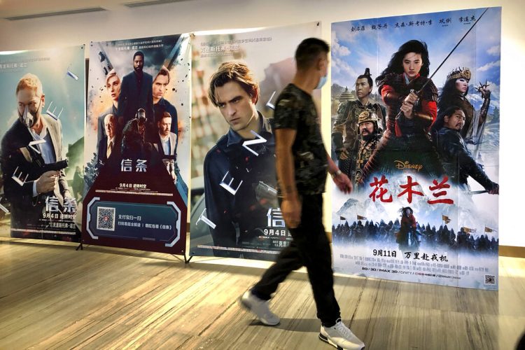 Un hombre con mascarilla pasa junto a un afiche de la película de Disney "Mulan" en un cine en Beijing, el 11 de septiembre del 2020.  Foto: Mark Schiefelbein/AP.
