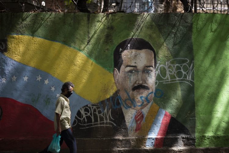 Un individuo con mascarilla pasa frente a un mural del presidente Nicolás Maduro en Caracas el 22 de julio de 2020. Foto: Ariana Cubillos/AP.