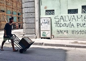 Un joven con nasobuco lleva un televisor en una carretilla, en La Habana. Foto: Ernesto Mastrascusa / EFE.