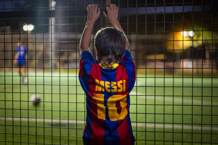 Un niño con una camiseta de Lionel Messi observa un partido de fútbol en Banyoles, España. Foto: Emilio Morenatti/AP/archivo.