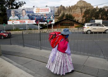 Una mujer camina cerca de una valla con propaganda electoral en El Alto, Bolivia, el sábado 17 de octubre de 2020. Foto: Juan Karita/AP.