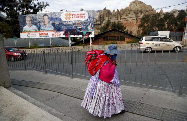 Una mujer camina cerca de una valla con propaganda electoral en El Alto, Bolivia, el sábado 17 de octubre de 2020. Foto: Juan Karita/AP.