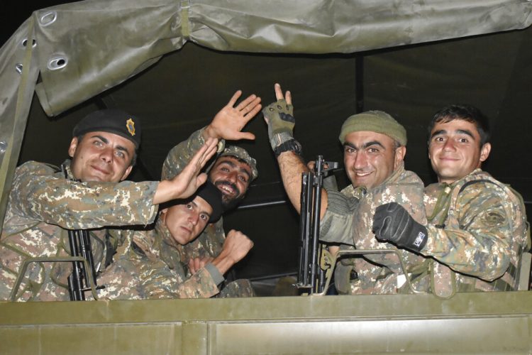 En esta imagen difundida el martes 6 de octubre de 2020, soldados armenios saludan a un fotógrafo mientras viajan en la parte trasera de un camión durante el combate con fuerzas de Azerbaiyán en la autoproclamada República de Nagorno Karabaj, el domingo 4 de octubre de 2020. Foto: Oficina de prensa del Ministerio de Defensa de Armenia, vía AP.