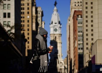 Fotografía del 8 de noviembre de 2020 de una persona con mascarilla cruzando la calle Broad en Filadelfia. Foto: Matt Slocum/AP.