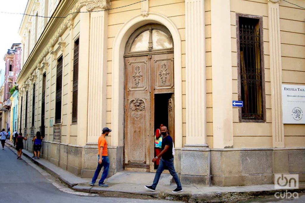 Unas personas pasan frente a una puerta exterior en La Habana. Foto: Otmaro Rodríguez.